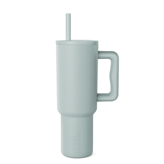 Sage green signature tumbler with handle and reusable straw, displayed on white background. Modern drinkware design with soft muted color and cylindrical shape.